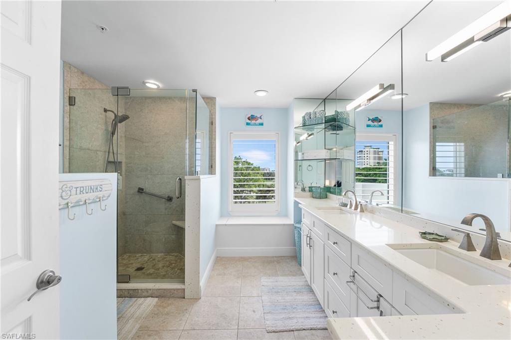Bathroom featuring double vanity, light tile patterned flooring, and a stall shower