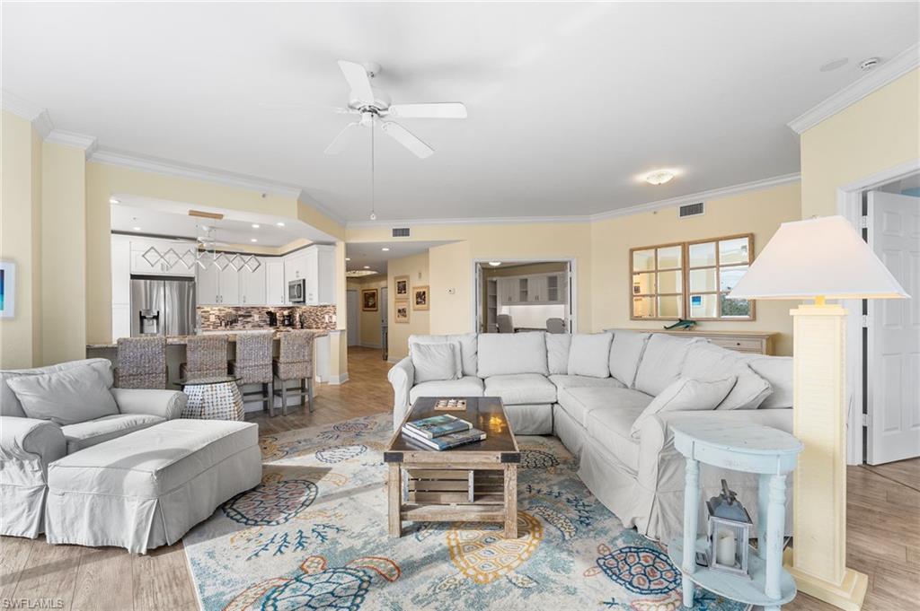 Living room with ornamental molding, light wood finished floors, and ceiling fan