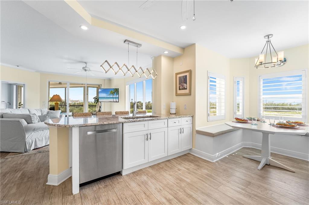 Kitchen featuring recessed lighting, light stone countertops, a peninsula, stainless steel dishwasher, and white cabinetry