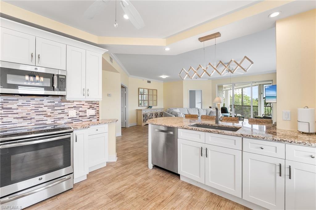 Kitchen with appliances with stainless steel finishes, white cabinetry, light stone countertops, open floor plan, and recessed lighting