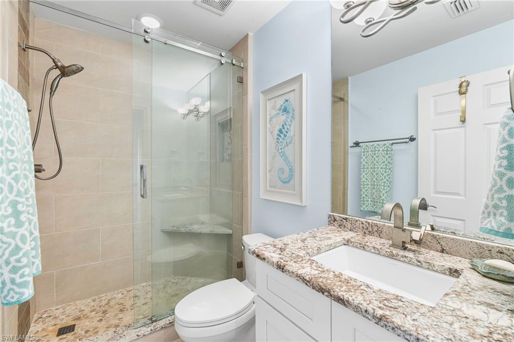 Bathroom featuring a shower stall, vanity, and a chandelier