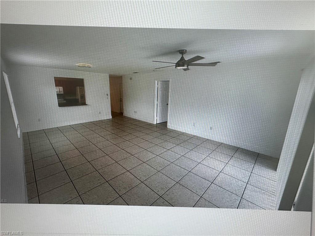 Unfurnished living room with tile patterned floors, a ceiling fan, and wallpapered walls