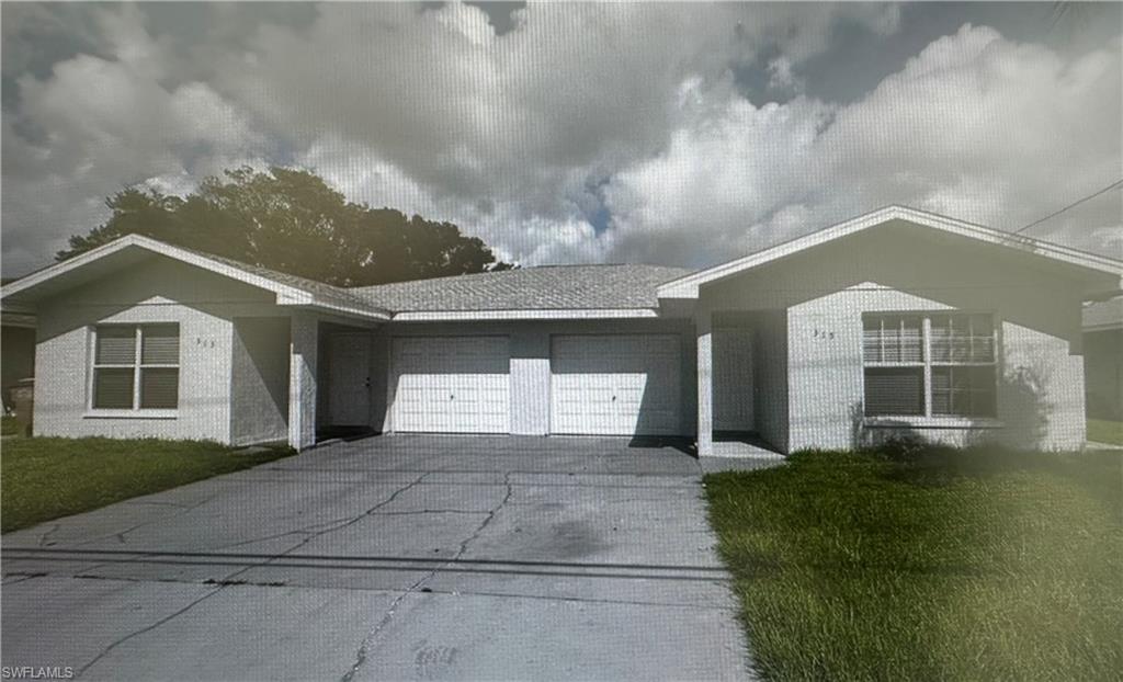 View of front of home with a garage, driveway, and a front lawn