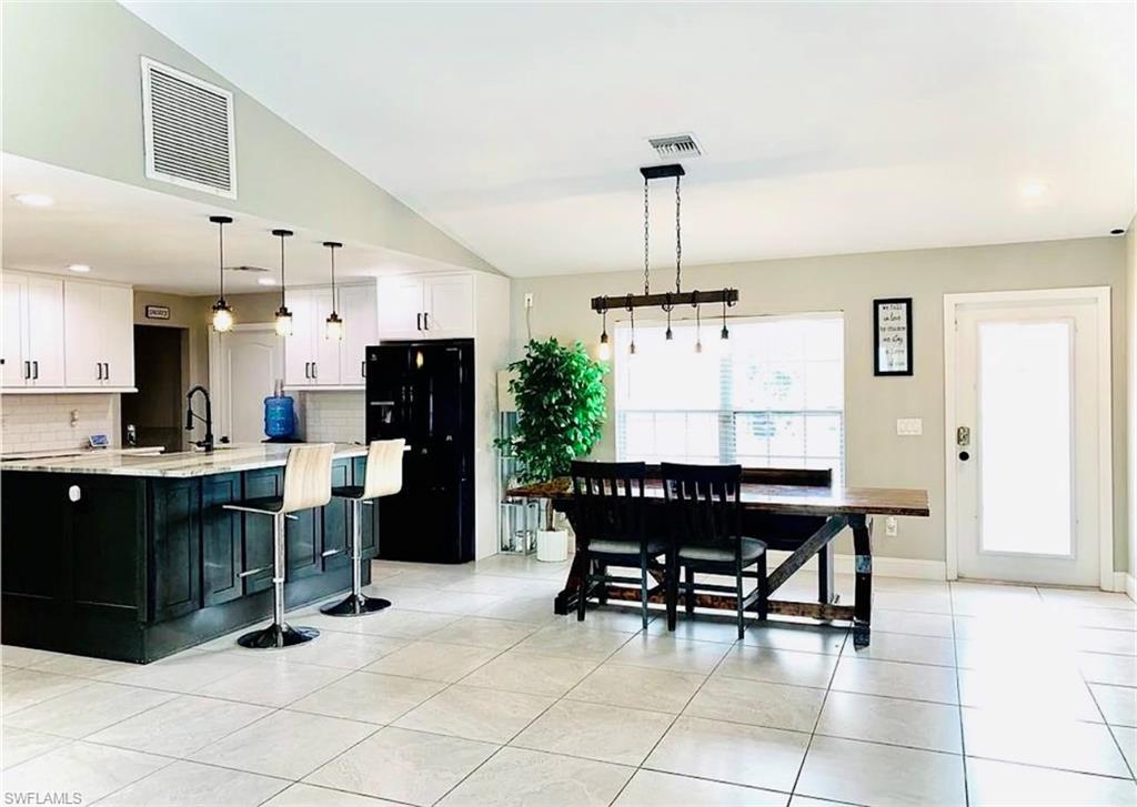Kitchen with dark cabinets, recessed lighting, freestanding refrigerator, pendant lighting, and light tile patterned flooring