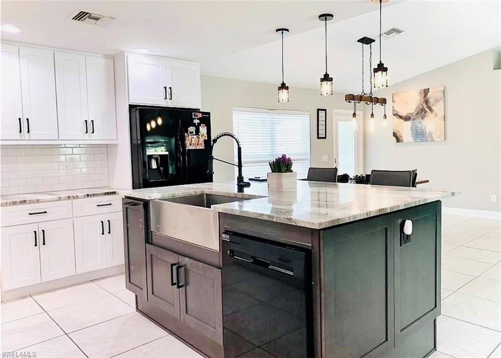 Kitchen with light tile patterned flooring, light stone countertops, white cabinetry, lofted ceiling, and recessed lighting