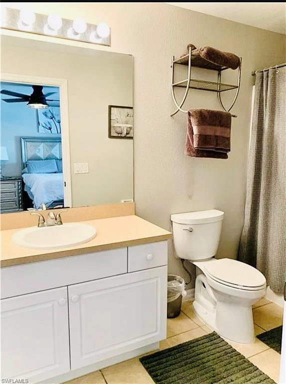Ensuite bathroom featuring light tile patterned flooring, vanity, and curtained shower