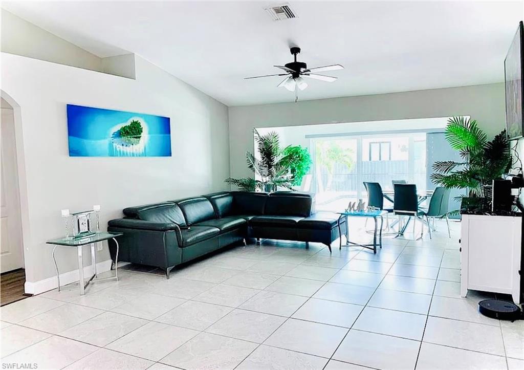 Living area with arched walkways, light tile patterned floors, and a ceiling fan