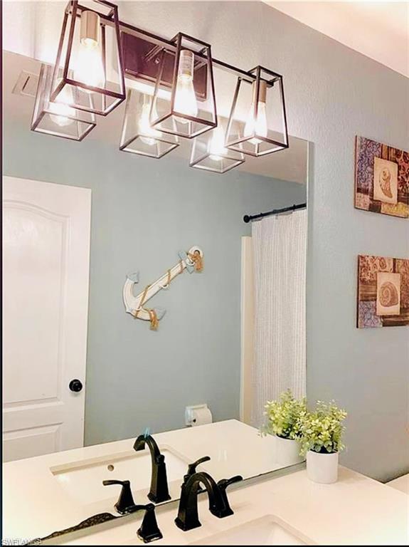 Bathroom with a chandelier, vanity, and a shower with shower curtain