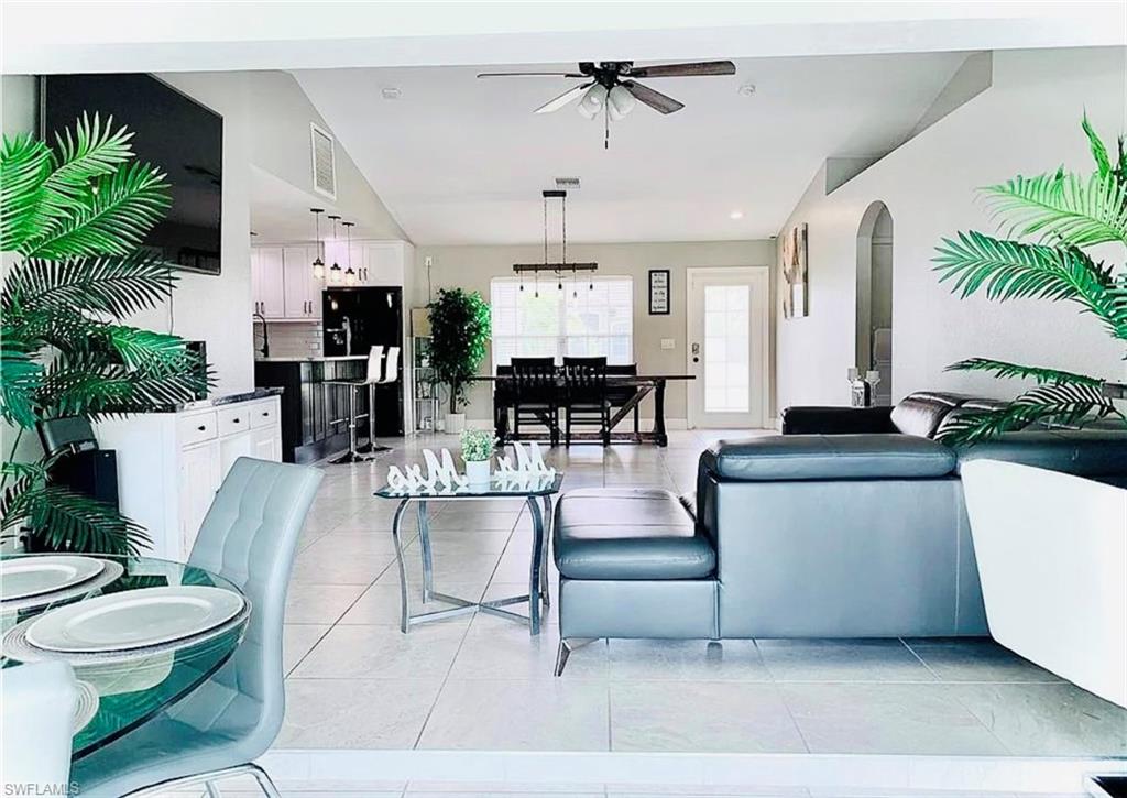 Living room with light tile patterned flooring, ceiling fan, and arched walkways