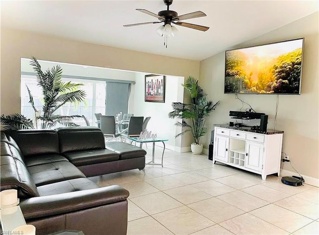 Living area featuring light tile patterned floors, a ceiling fan, and vaulted ceiling