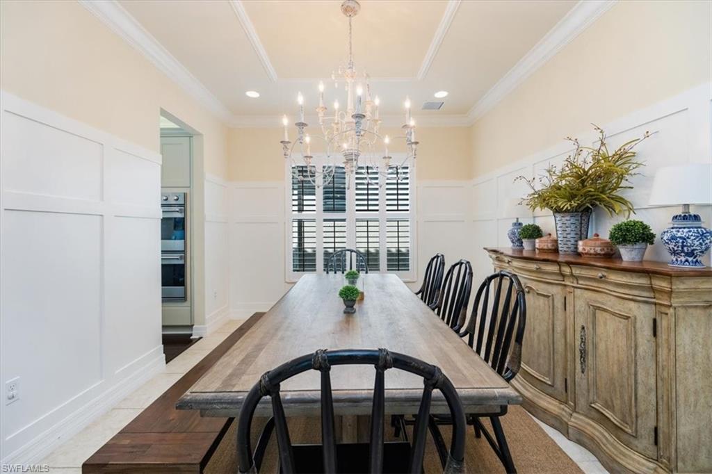 Dining space featuring ornamental molding, light tile patterned flooring, and a notable chandelier