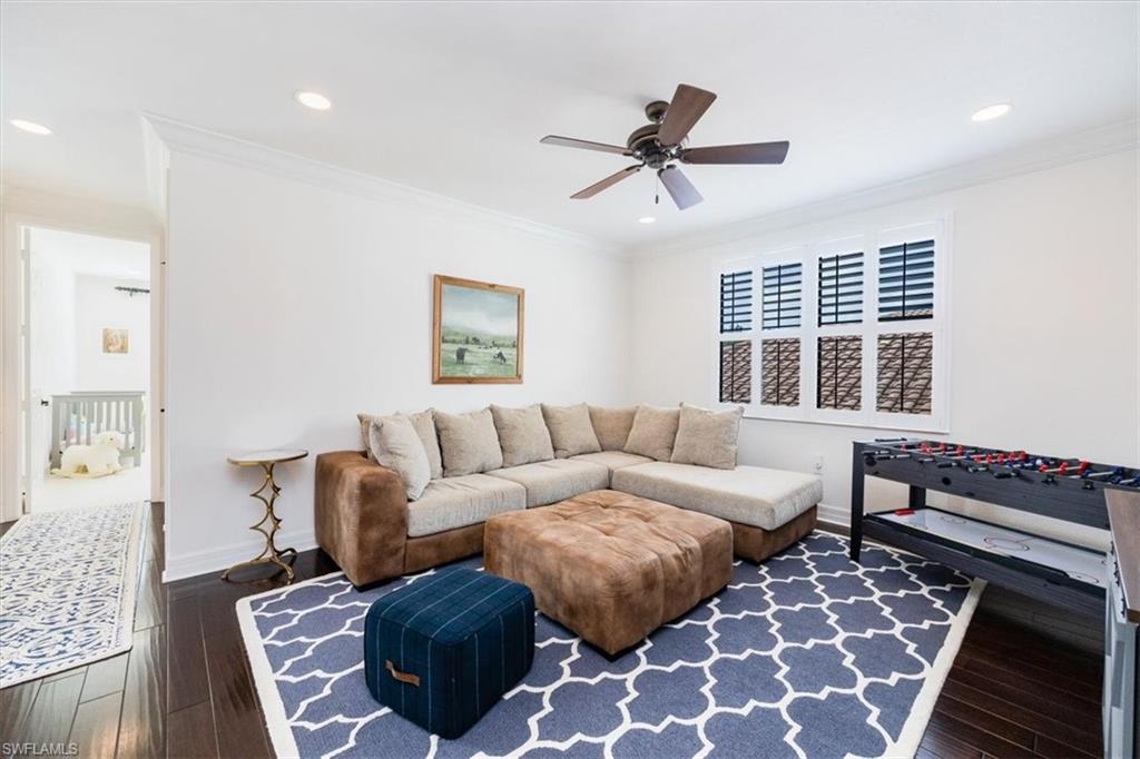 Living room with dark hardwood / wood-style flooring, ceiling fan, and crown molding