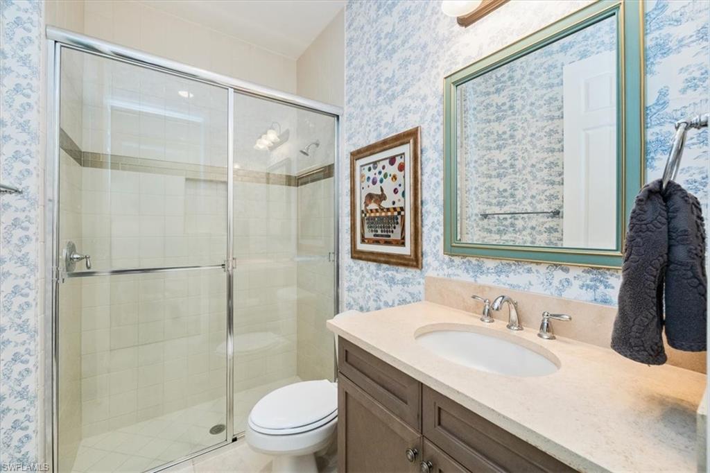 Bathroom with toilet, an enclosed shower, and vanity