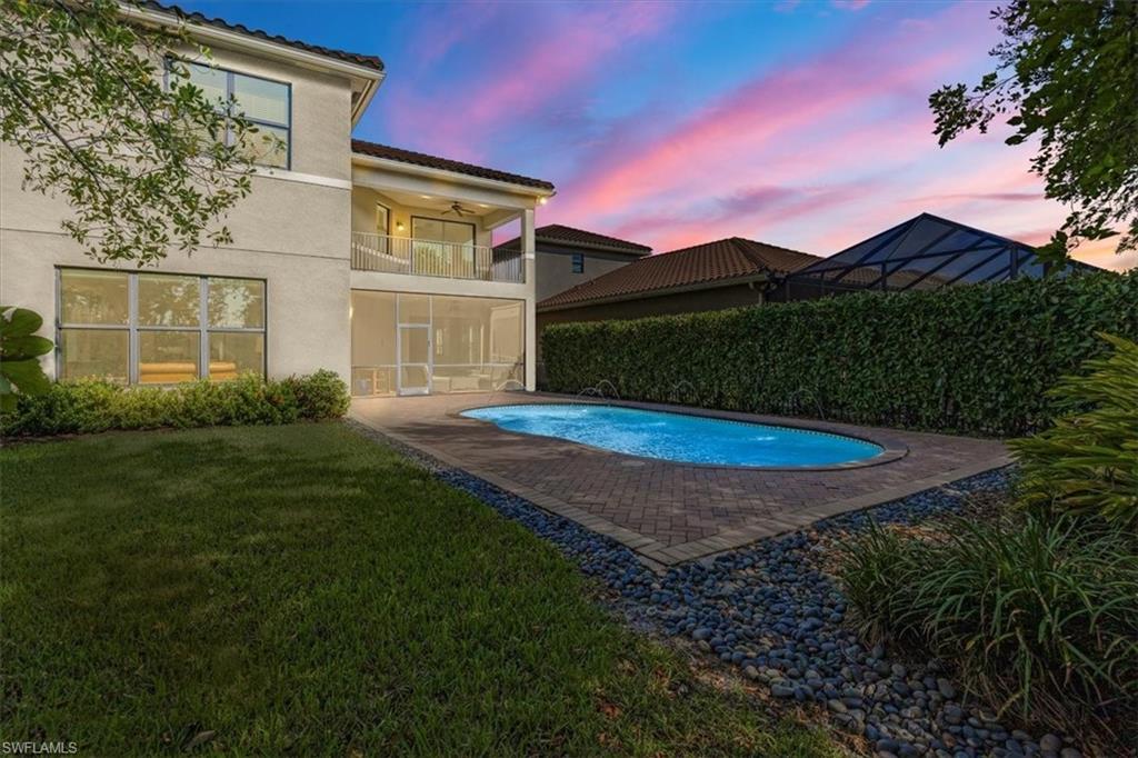 Pool at dusk featuring a patio, ceiling fan, and a yard