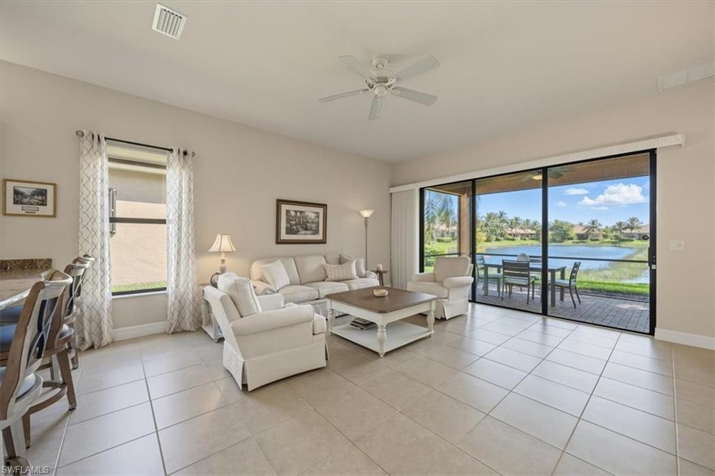 Living room featuring light tile patterned floors, ceiling fan, and a water view