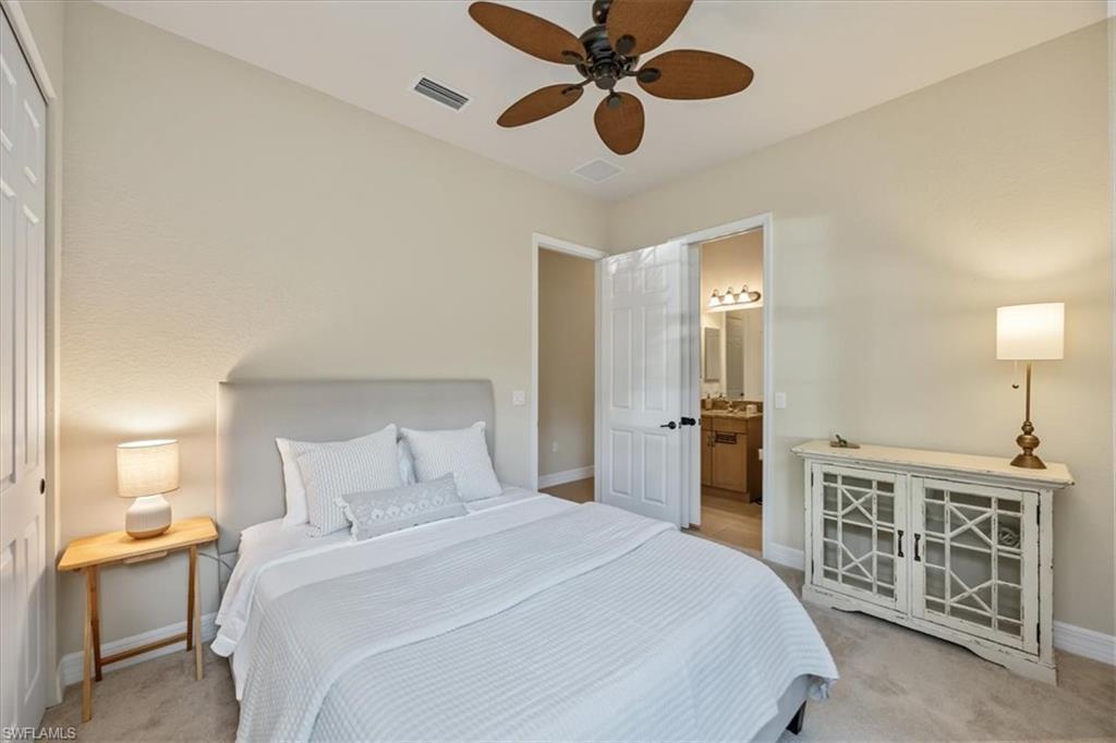 Bedroom with light colored carpet, a ceiling fan, and ensuite bath