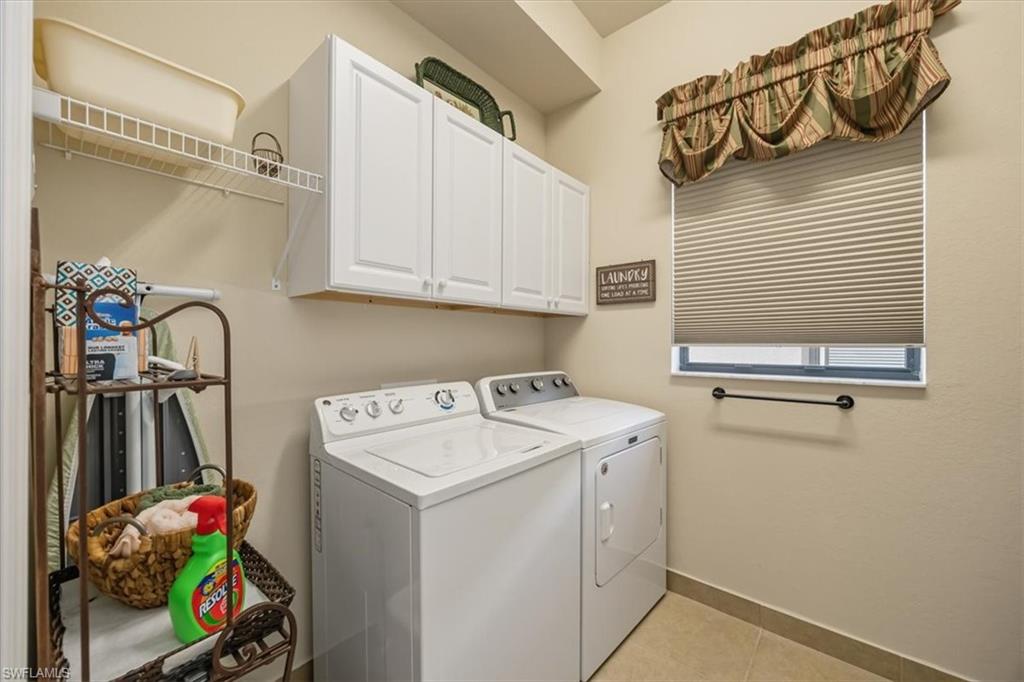 Laundry room with cabinet space, light tile patterned floors, and washer and clothes dryer