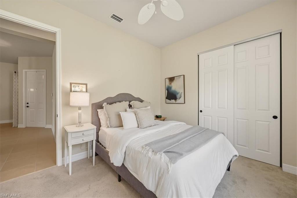 Bedroom with light carpet, a closet, ceiling fan, and light tile patterned flooring
