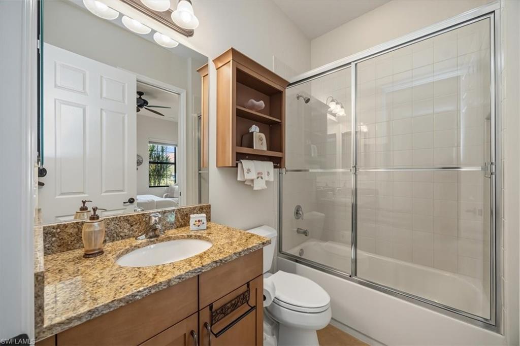 Bathroom featuring bath / shower combo with glass door, vanity, ensuite bathroom, and a ceiling fan