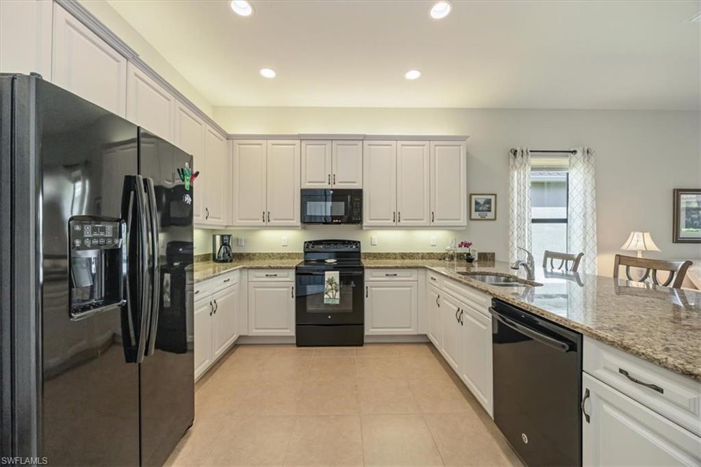 Kitchen with black appliances, light stone counters, white cabinetry, a peninsula, and recessed lighting