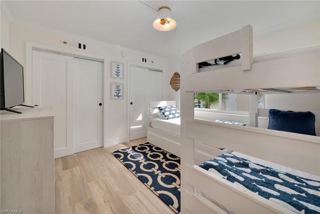 Bedroom featuring two closets, light wood finished floors, and ornamental molding