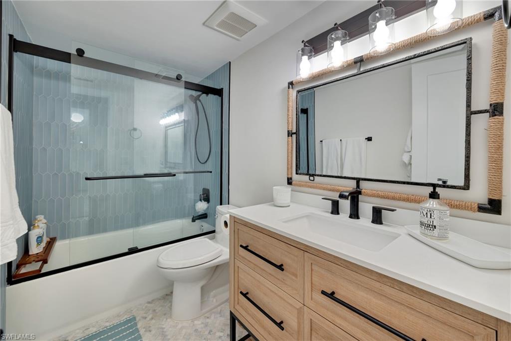 Full bathroom with shower / bath combination with glass door and vanity