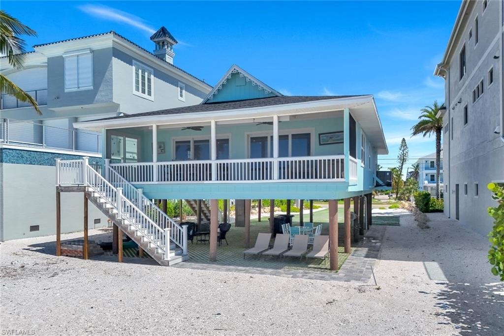 View of front of property with ceiling fan, stairs, a patio area, covered porch, and roof with shingles