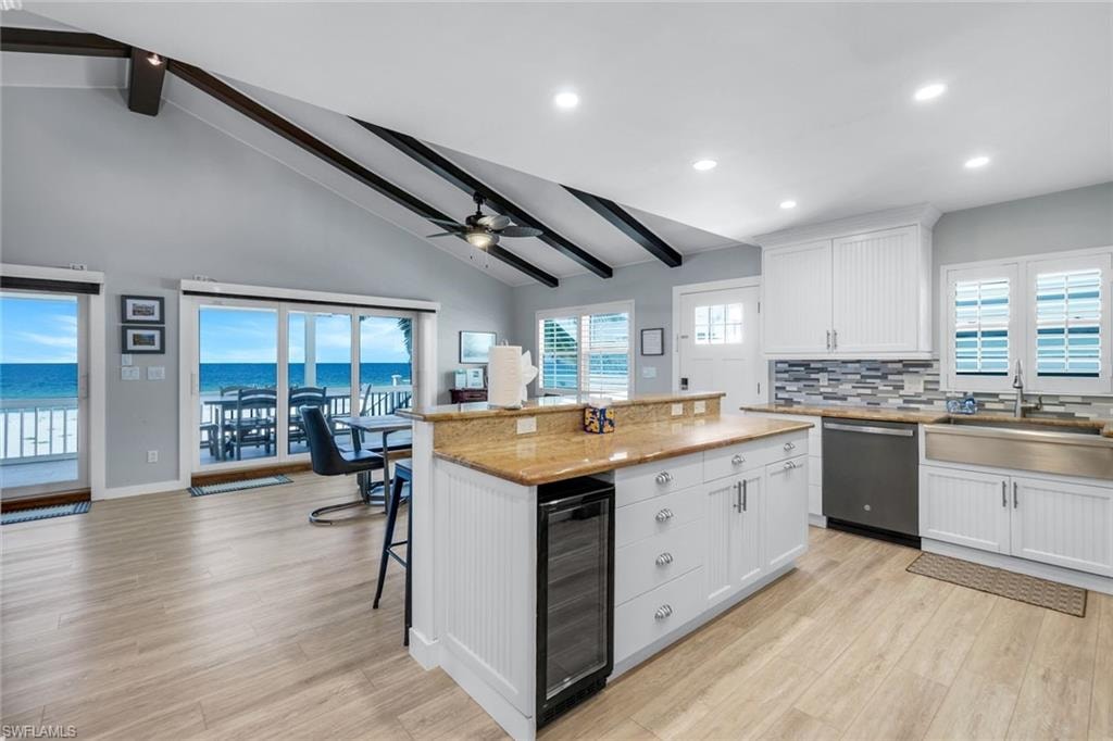Kitchen featuring beamed ceiling, white cabinetry, backsplash, healthy amount of natural light, and high vaulted ceiling