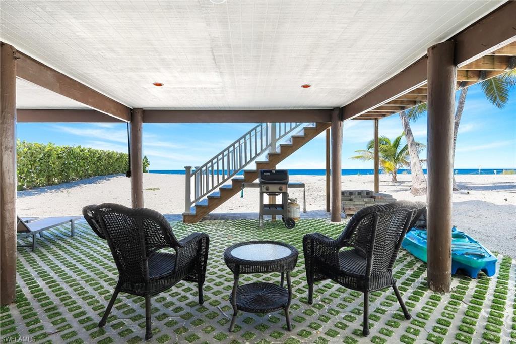 View of patio / terrace with view of water and beach, area for grilling, and stairs
