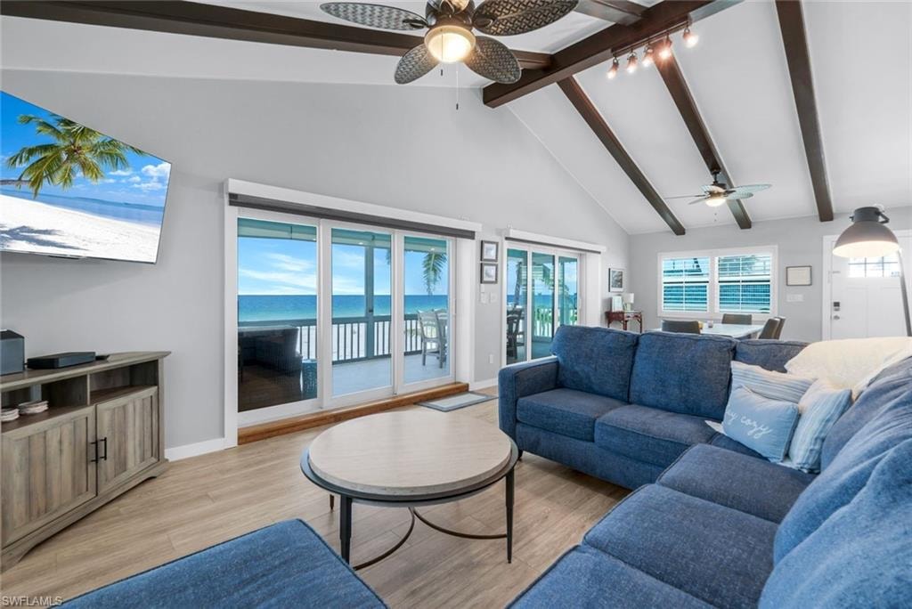 Living room with beam ceiling, light wood-type flooring, high vaulted ceiling, and a ceiling fan