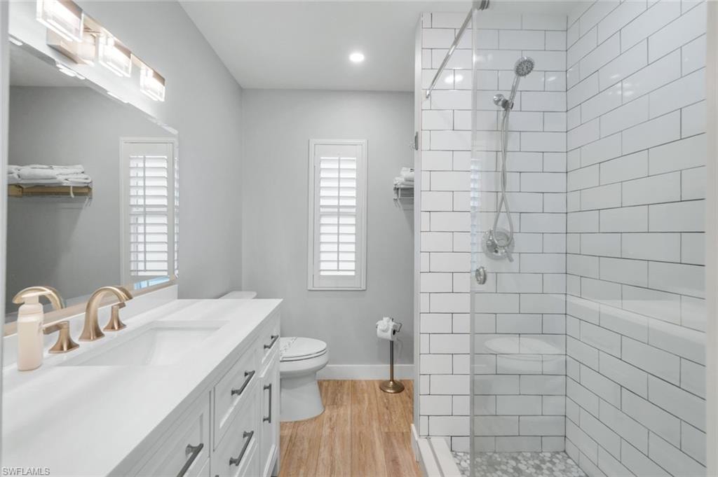 Full bath with vanity, a walk in shower, light wood-style floors, and recessed lighting