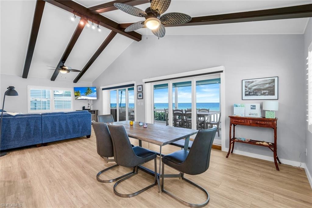 Dining area with healthy amount of natural light, beam ceiling, high vaulted ceiling, light wood-style flooring, and ceiling fan