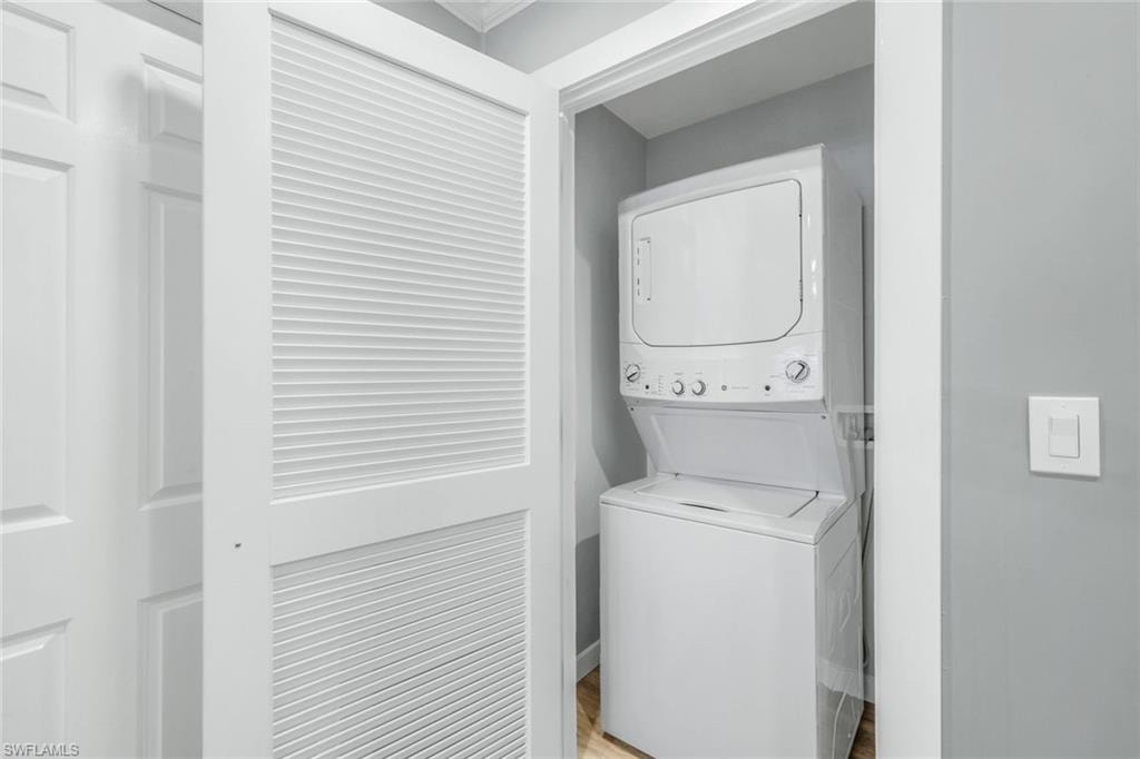 Laundry room with stacked washer / drying machine and light wood-type flooring