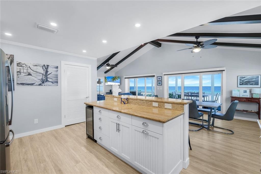 Kitchen featuring white cabinets, a center island, light wood finished floors, healthy amount of natural light, and recessed lighting