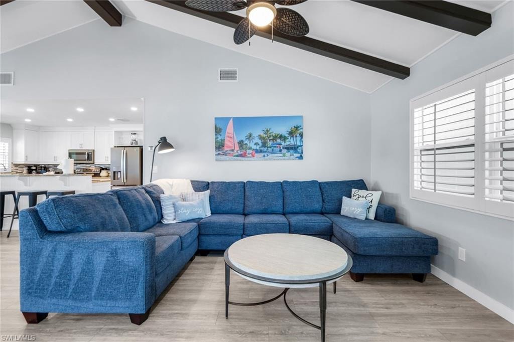 Living room featuring beamed ceiling, light wood-type flooring, and high vaulted ceiling