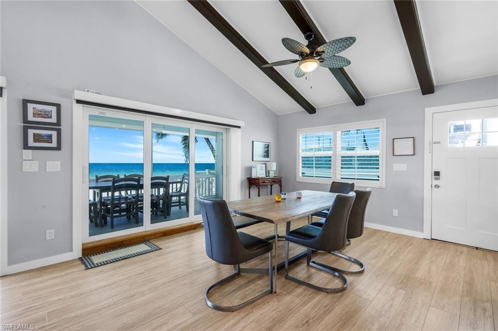 Dining area featuring light wood finished floors, beam ceiling, high vaulted ceiling, a water view, and ceiling fan