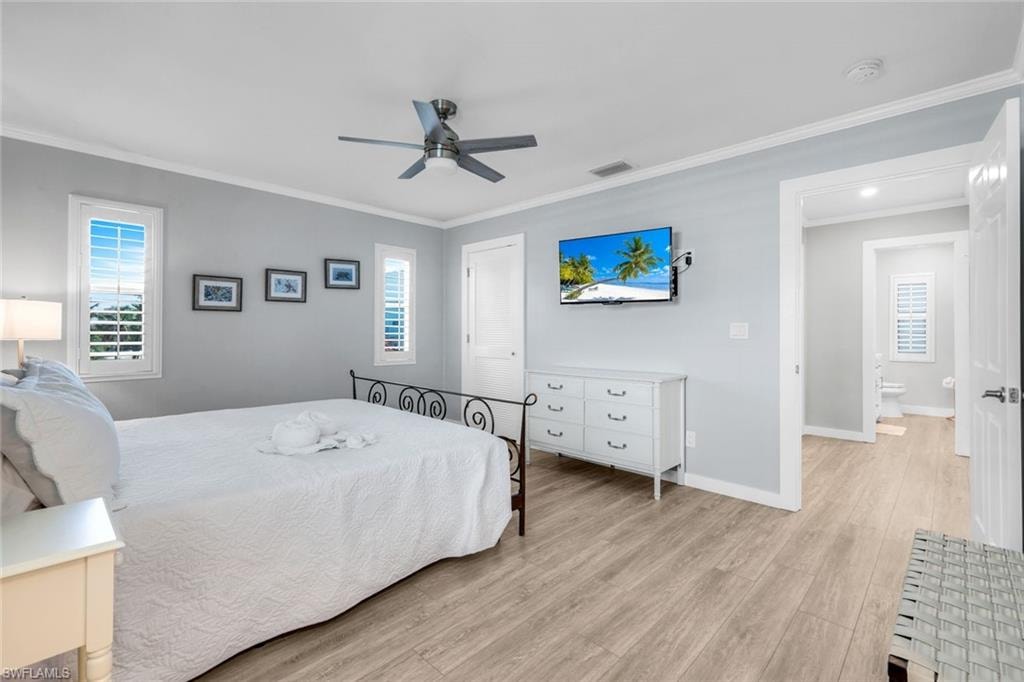Bedroom with light wood-style floors, ornamental molding, a ceiling fan, and a closet