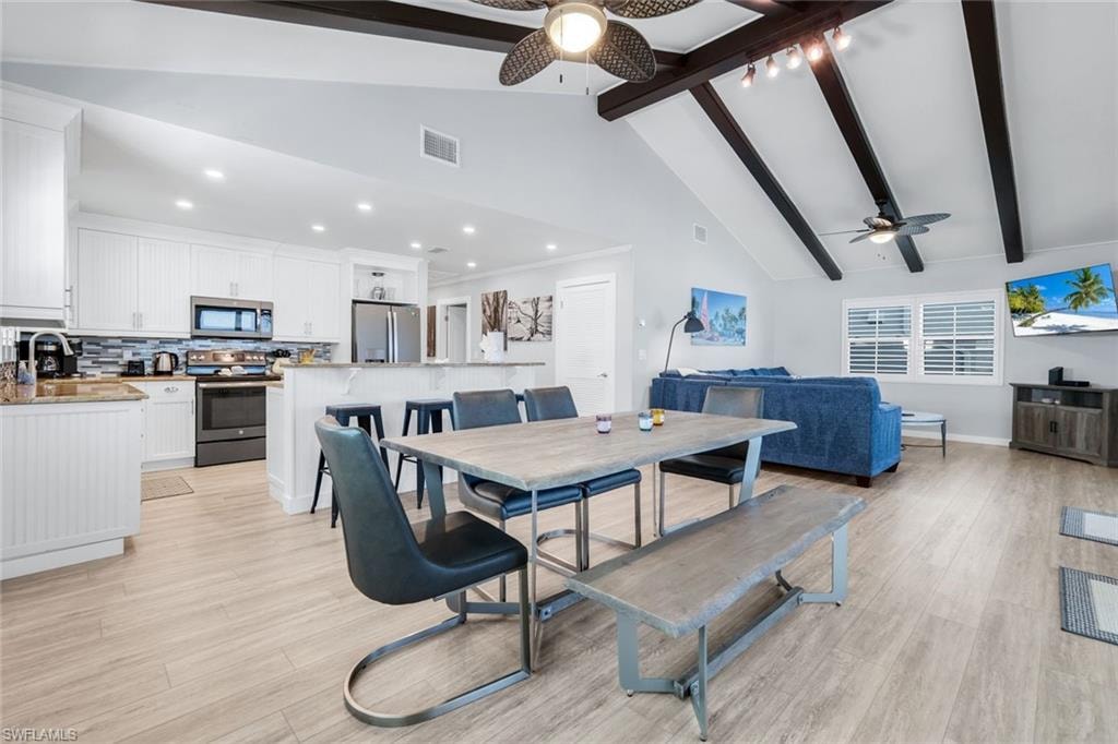 Dining space featuring beam ceiling, ceiling fan, high vaulted ceiling, light wood finished floors, and recessed lighting
