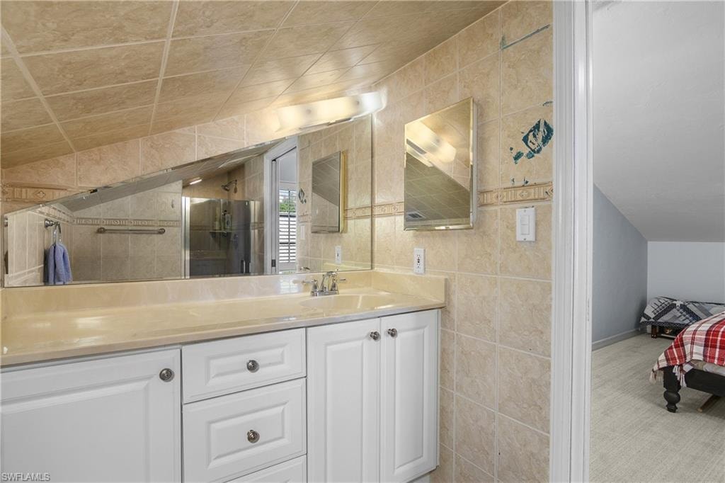 Ensuite bathroom featuring tile walls, vanity, and a shower stall