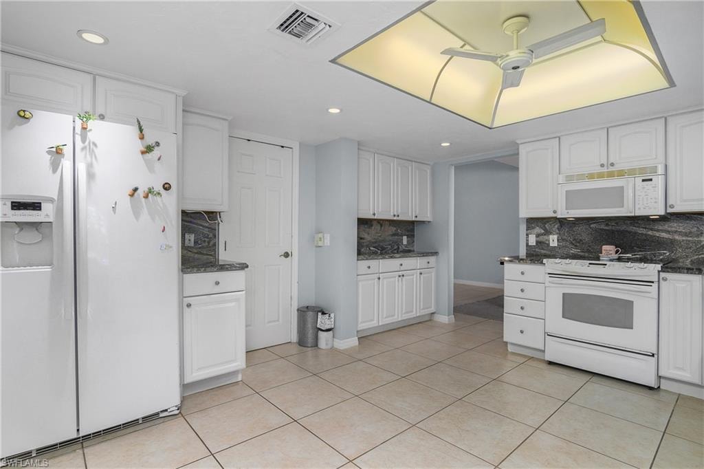 Kitchen with white appliances, white cabinets, light tile patterned floors, decorative backsplash, and recessed lighting