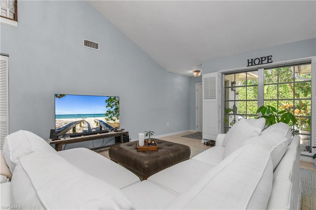 Tiled living room featuring high vaulted ceiling and baseboards