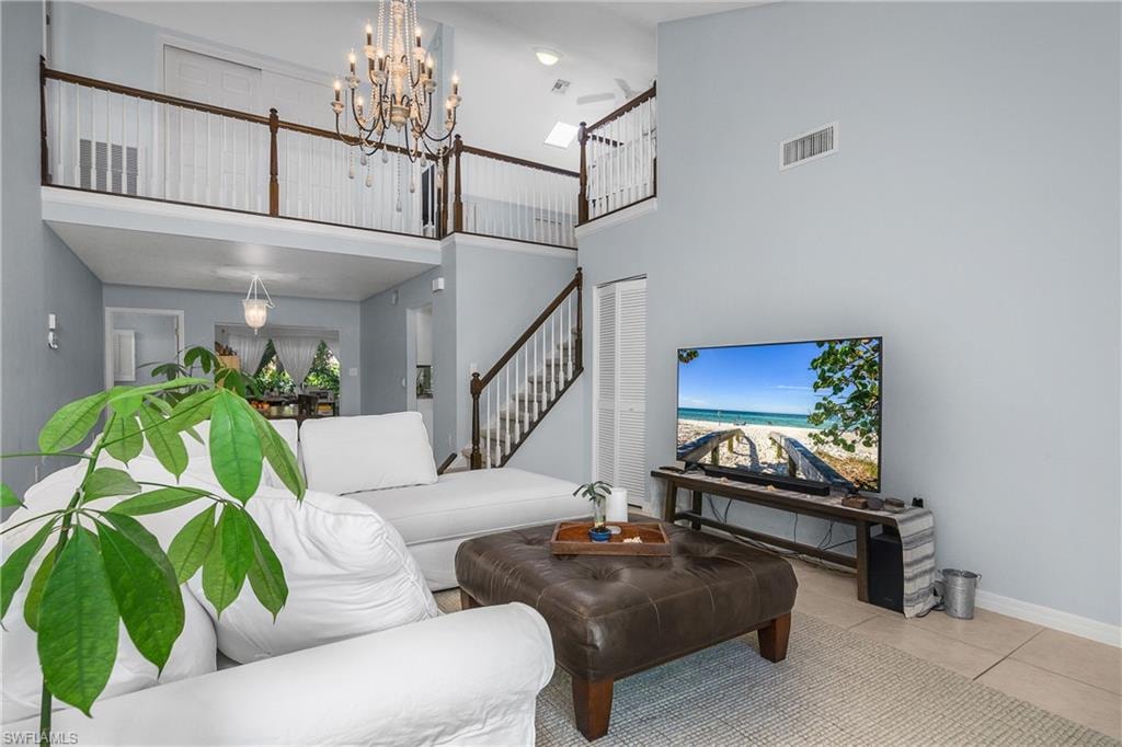 Tiled living room with a high ceiling, a chandelier, and stairs