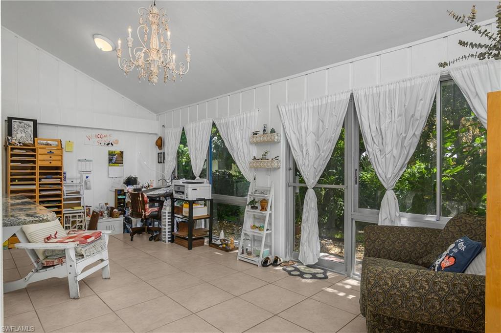 Office area with vaulted ceiling, light tile patterned floors, and a chandelier