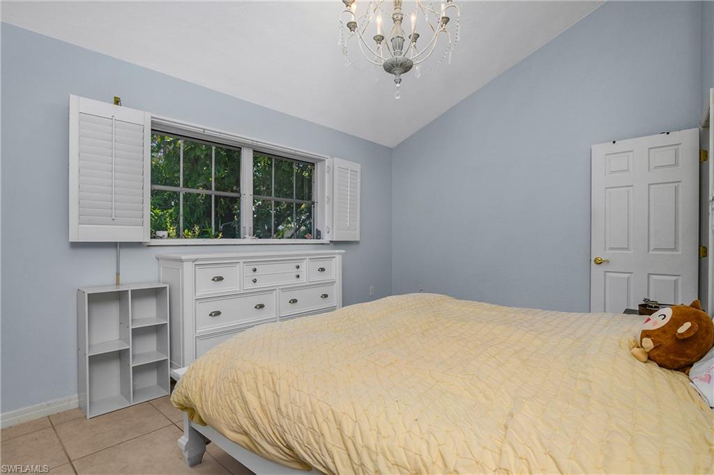 Bedroom with vaulted ceiling, light tile patterned floors, and a chandelier