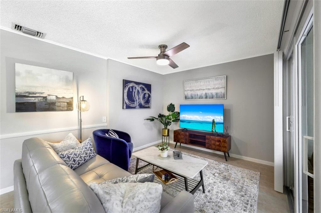 Living area with a textured ceiling, a ceiling fan, and light tile patterned flooring