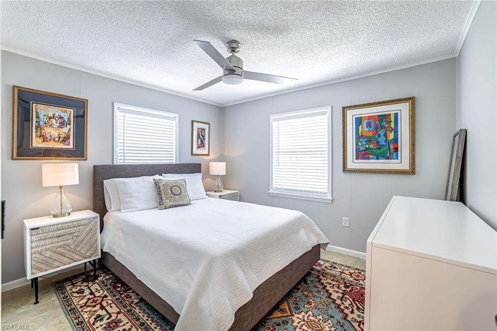 Bedroom featuring a textured ceiling, ceiling fan, and ornamental molding