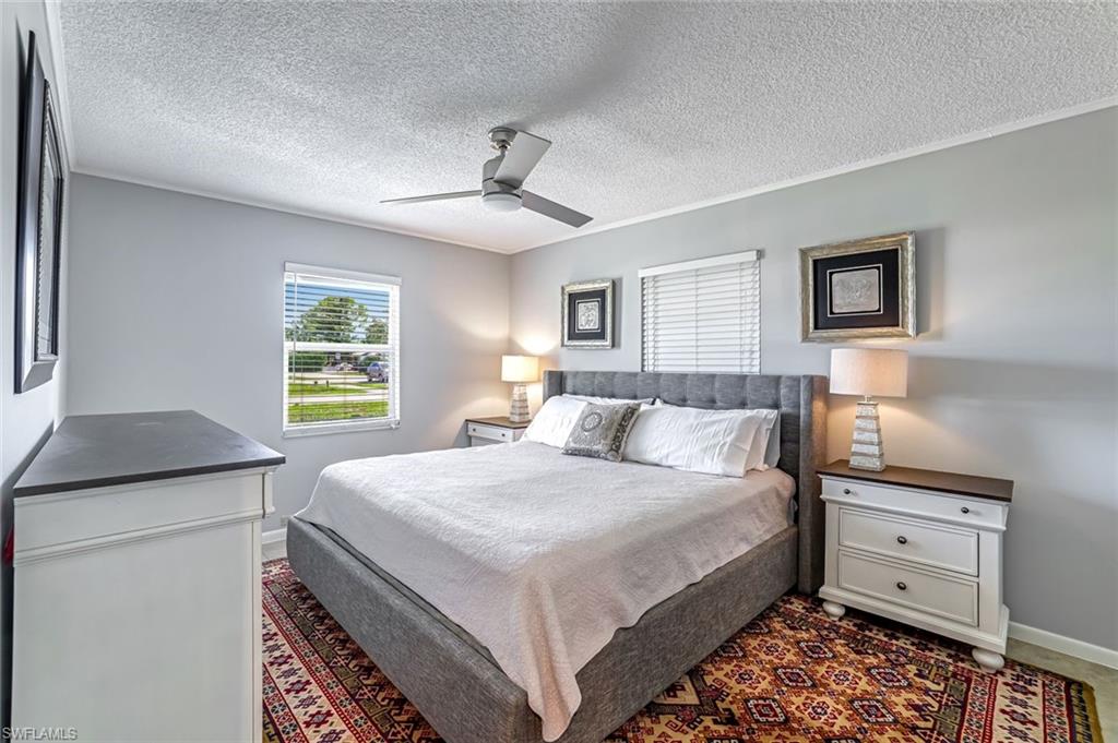 Bedroom with a textured ceiling, a ceiling fan, and crown molding