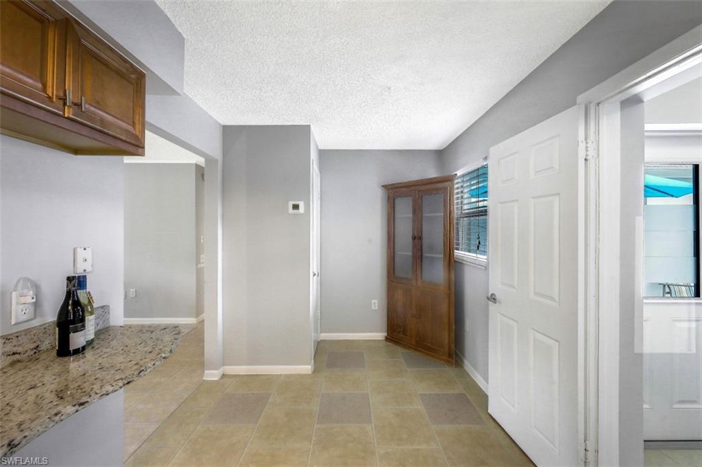 Hall with a textured ceiling, light tile patterned floors, and plenty of natural light