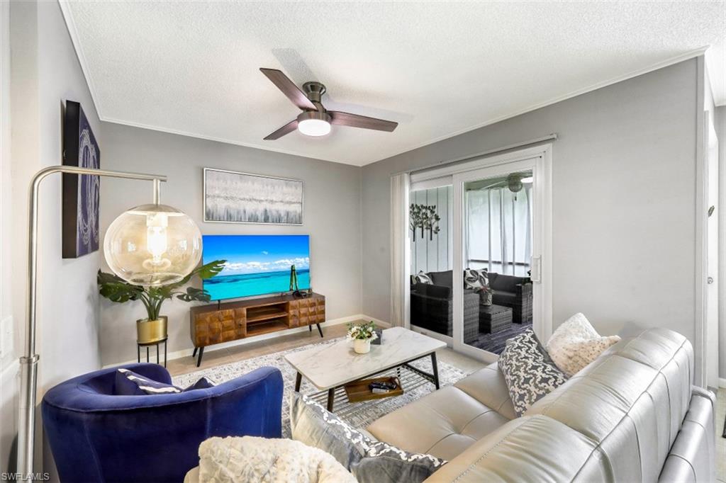 Living area with a textured ceiling, ceiling fan, and crown molding
