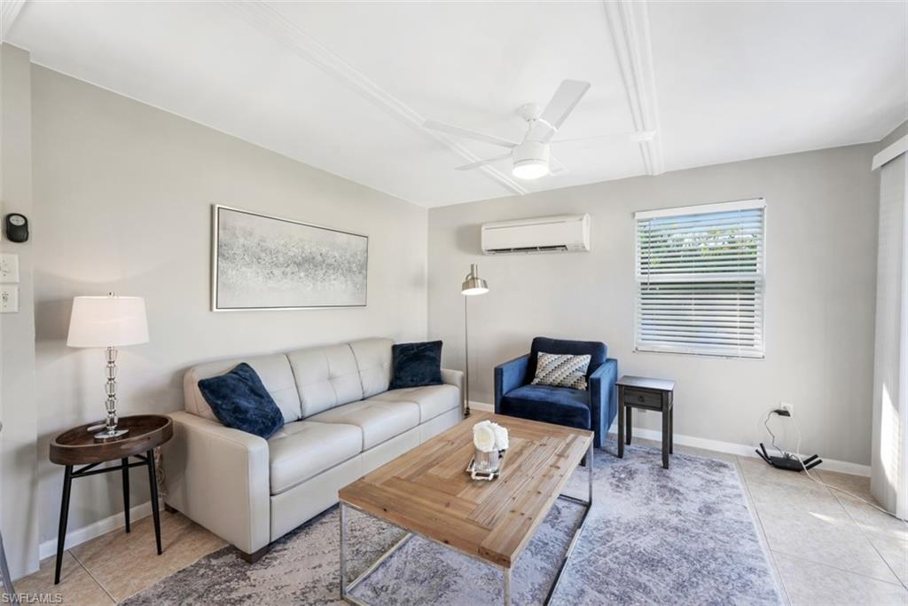 Living area featuring light tile patterned floors, ceiling fan, and a wall mounted AC